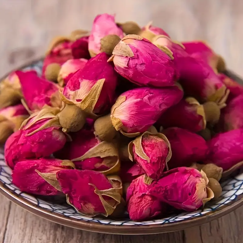 The dried roses are tightly closed in shades of deep crimson red, sometimes with a few loose petals or the occasional brown bud.